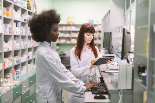 Digital pharmacists working on computer and tablet in modern pharmacy