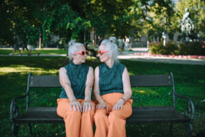 Happy senior twins sitting in city park